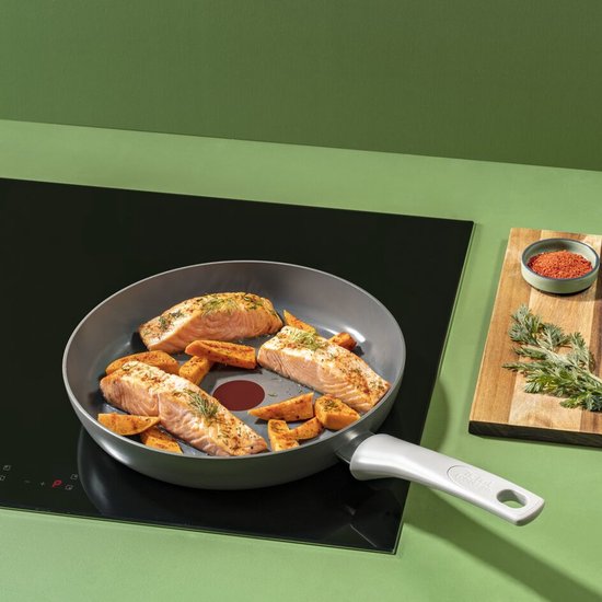 Filets de saumon et morceaux de patate douce cuisant dans une poêle avec Thermo-Signal sur une plaque à induction.