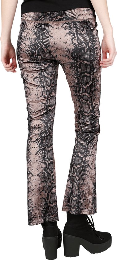 Achterkant van een model in een bruine legging met zwart slangenprintpatroon, uitlopende pijpen en platformlaarzen.