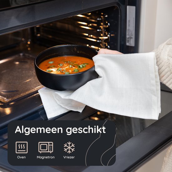 Zwarte kom met soep wordt uit magnetron gehaald.