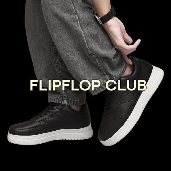 Man in grijze jeans draagt zwarte Flipflop Club sneakers met witte zolen.