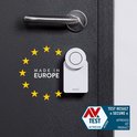 Witte Nuki Smart Lock op een zwarte deur met een metalen handgreep. Sterrenkrans met 'Made in Europe' en TEST resultaat 'Secure'.