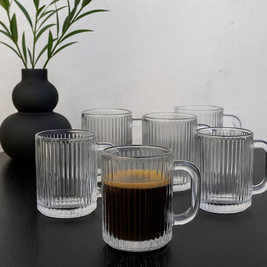Six tasses cannelées et transparentes avec anse, une remplie d'espresso.