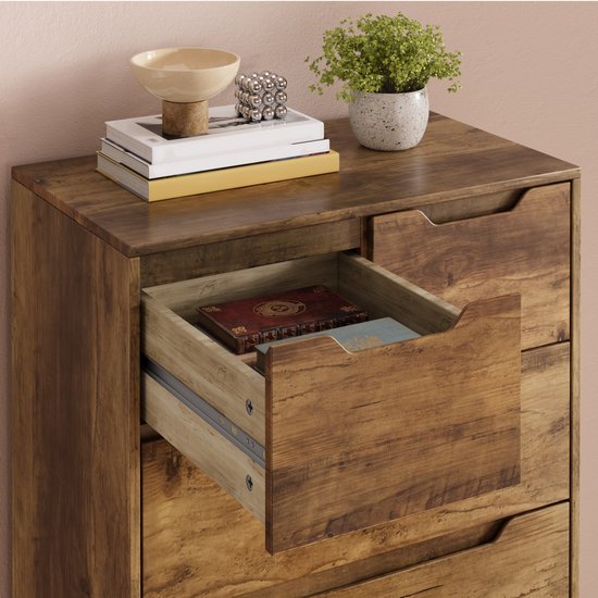 Commode marron clair avec un tiroir ouvert, contenant des livres et de la décoration. Détail grain de bois.