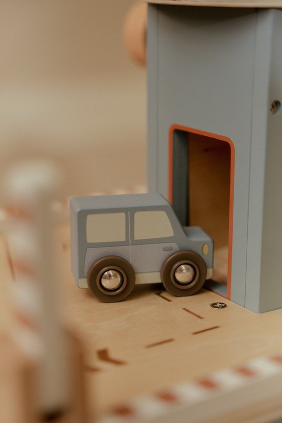 Gedetailleerde close-up van een houten blauwe speelgoedauto bij de ingang van een garage.