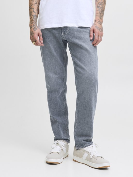 Model in grijze jeans met witte sneakers. De jeans hebben een rechte pasvorm en een lichte wassing.