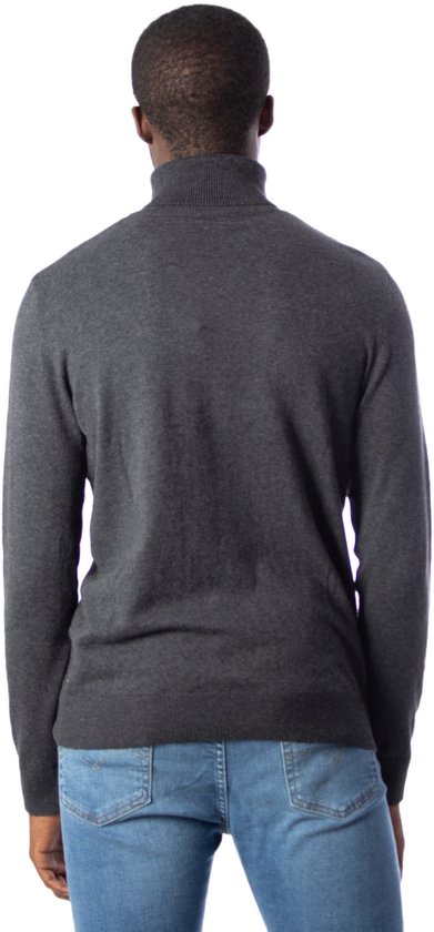 Achterkant van een man met donkergrijs coltrui en blauwe jeans.