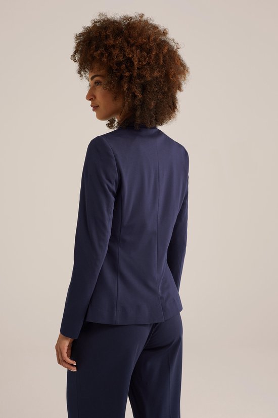Achterkant van een vrouw met een donkerblauwe blazer en bijpassende broek.