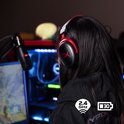 Vrouw met lange zwarte haren, draagt een zwarte en rode gaming headset.