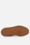 Bruine buitenzool van een roze Puma sneaker met groen accent.