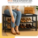 Vrouw zittend op een zwarte schoenenkast met 3 etages, schoenen aantrekkend. Text: Zit en trek je schoenen aan. Stevig houten blad voor comfortabel aantrekken.