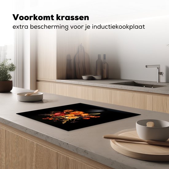 Zwarte inductiebeschermer met een boeket bloemen in herfstkleuren, geplaatst op een inductiekookplaat in een keuken.