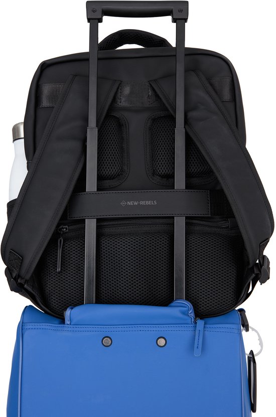 Zwarte rugzak op een blauwe koffer, met "NEW REBELS" logo.