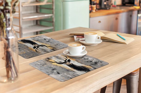 Deux sets de table avec un cerf abstrait aux bois dorés sur fond gris.