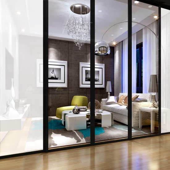 Modern ingerichte woonkamer met schuifdeuren, gezien vanaf buiten. Met een grote bank, salontafel en groen stoeltje.