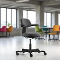 Zwarte bureaustoel met ergonomische rugleuning en verstelbare armleuningen op een zwarte voet met wieltjes.