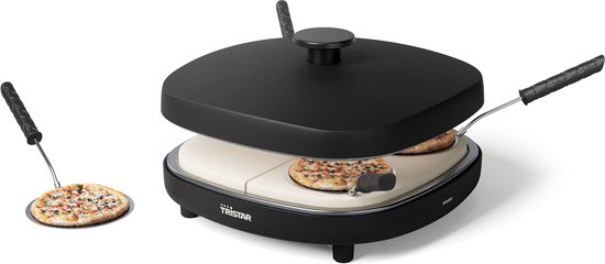 Zwarte pizzamaker met 2 mini-pizza's op de keramische plaat en een spatel met pizza ernaast.