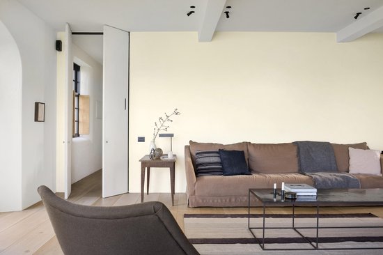 Bruine bank met dekens in een lichte woonkamer met open deur.