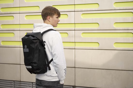 Jonge man draagt zwarte waterdichte Undercover Dsign rugzak met logo.