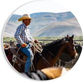 PVC Schuimplaat Muurcirkel - Cowboy op zijn Paard tussen Kudde bij Bergen - 20x20 cm Foto op Muurcirkel (met ophangsysteem)
