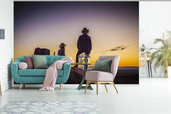 Deux cowboys dans une zone de montagne au coucher du soleil fotobehang