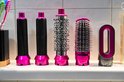 Verschillende opzetstukken voor een haarstyler, inclusief ronde borstels en een gladde opzetstuk, met roze accenten.