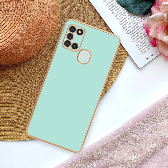 Mintgroen telefoonhoesje met gouden rand op een krant.