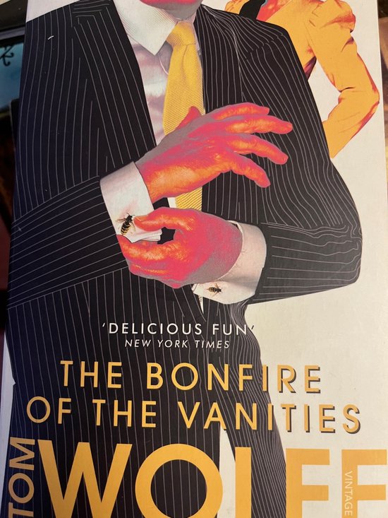Un homme en costume à rayures tennis avec une cravate jaune, mains vives et guêpes sur son poignet et mouchoir. Titre : THE BONFIRE OF THE VANITIES.