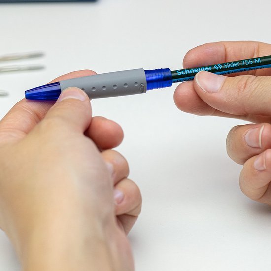 Handen plaatsen een grijze grip op een blauwe en zwarte Schneider Slider 755 M pen.