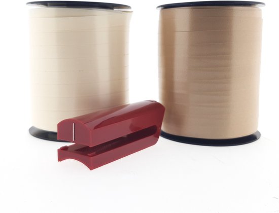 Un rouleau de ruban frisé couleur crème et un rouleau doré, avec un coupe-ruban rouge devant.