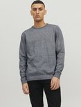Man met een donkerblauwe gebreide trui met ronde hals en zwarte jeans.