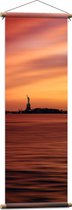 WallClassics - Affiche Textile - Statue de la Liberté à New York de loin avec Coucher de Soleil - 40x120 cm Photo sur Textile