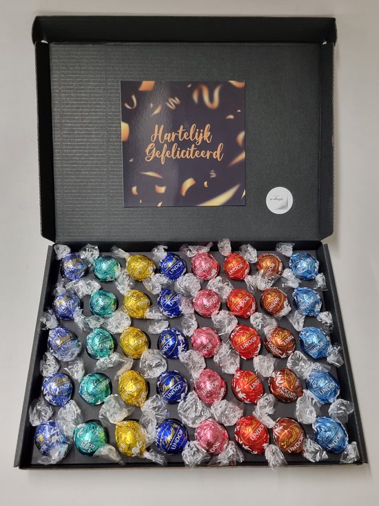 Zwarte doos met 40 Lindt chocoladeballen, gerangschikt per kleur. Een kaart met "Hartelijk Gefeliciteerd" ligt in de deksel.