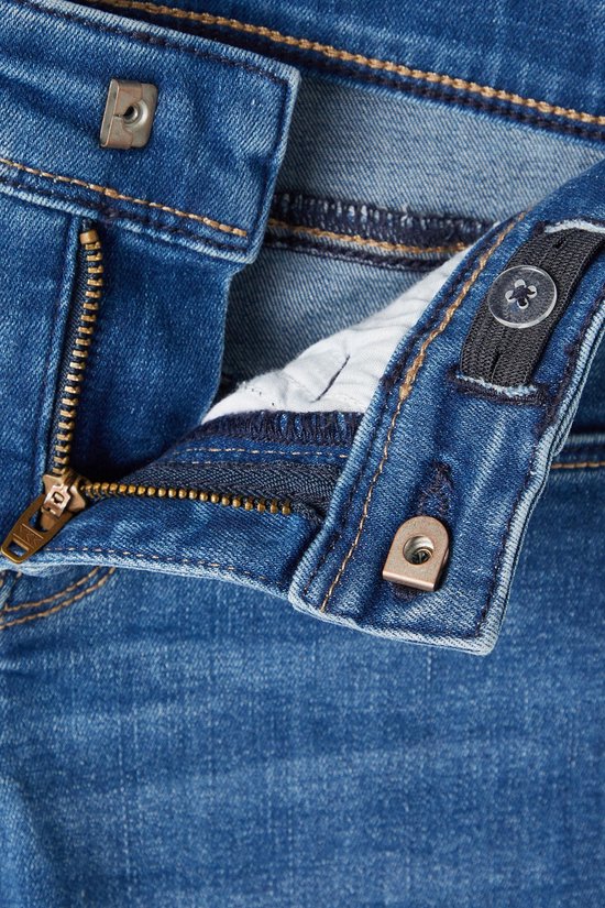 Detail van de tailleband van de jeans met rits en knoop.