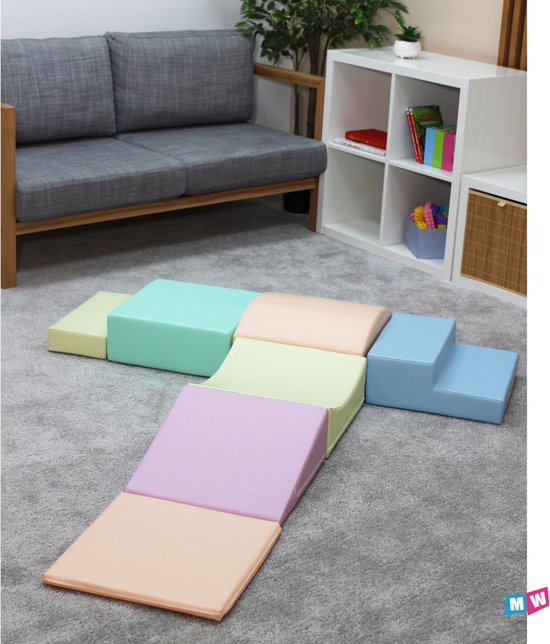 Blocs de jeu souples aux couleurs pastel, disposés en parcours avec des pentes, des marches et un arc.