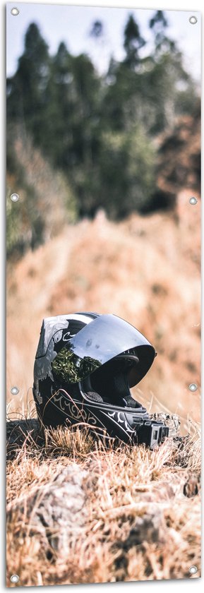 WallClassics - Tuinposter – Foto van Motorhelm door Droge Grassen - 50x150 cm Foto op Tuinposter (wanddecoratie voor buiten en binnen)