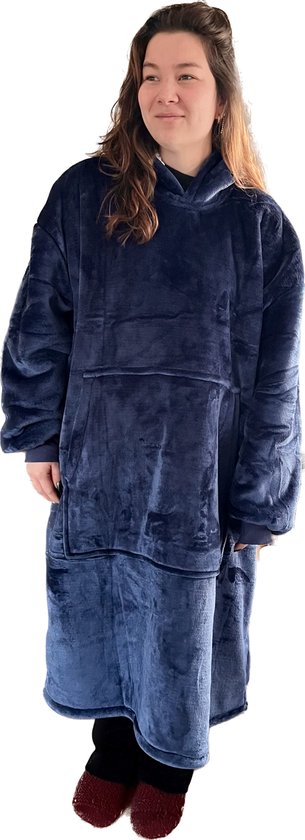 Een vrouw met lang bruin haar, die een donkerblauwe hoodie draagt, staat en kijkt naar de zijkant.