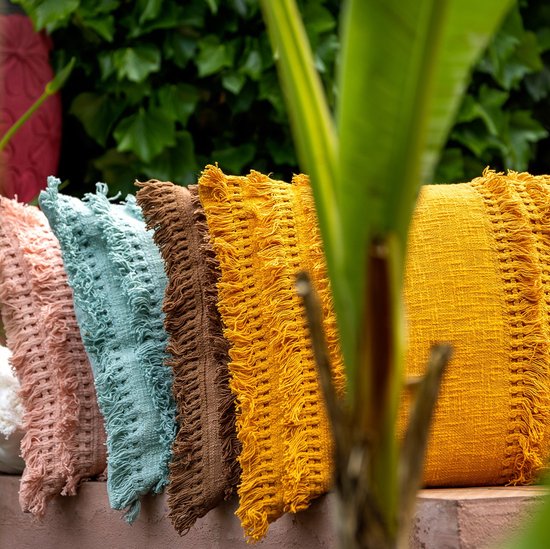 Rangée de coussins décoratifs de différentes couleurs, dont blanc, rose, bleu clair, marron et ocre avec des franges.