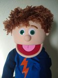 Close-up van handpop Tommie met warrig bruin haar en grote groene ogen.