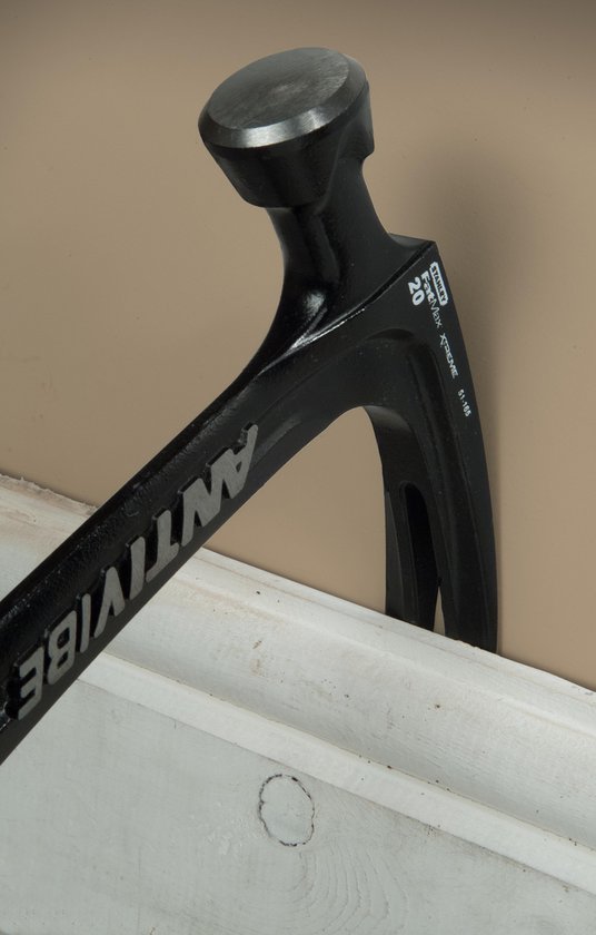 Zwarte Stanley FatMax Xtreme Antivibe klauwhamer met tekst, gebruikt op een witte plint naast een beige muur.