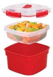 Base rouge de cuiseur vapeur avec un insert et un couvercle transparents, remplis de carottes et de haricots verts.