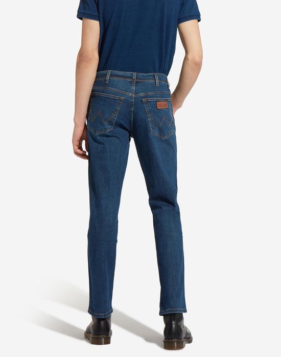 Man in blauwe jeans, achterkant weergave met bruine stiksels.