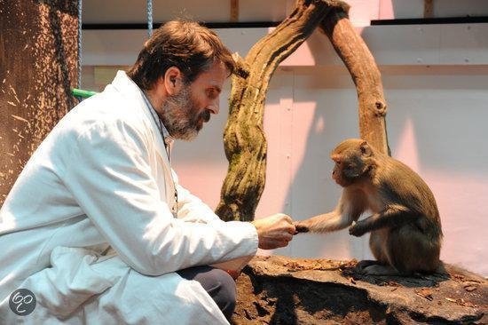 Man met baard in witte labjas, die een aap vasthoudt.