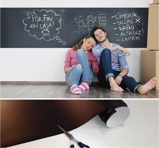 Een stel zit op de grond voor een zwart schoolbord. Er liggen verhuisdozen.