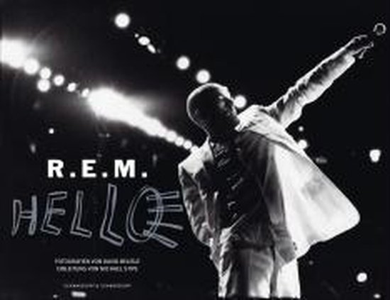 Michael Stipe van R.E.M. in een wit pak op een podium. "R.E.M. HELLO" staat op de voorgrond.