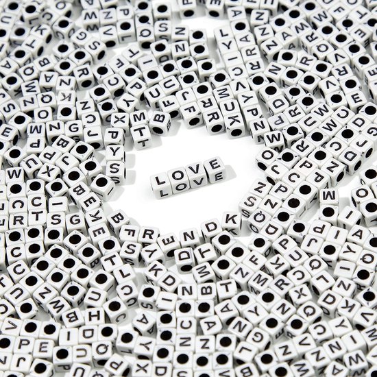 Veel witte letterkralen met zwarte letters verspreid, met 'LOVE' in het midden.