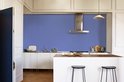 Moderne keuken met witte kasten, RVS afzuigkap en een blauwe muur.