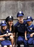 Twee volwassenen en twee kinderen in politie kostuums, lachend.