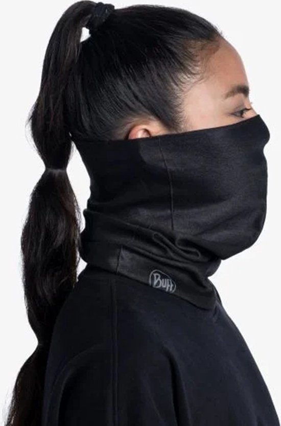 Vrouw met paardenstaart draagt een zwarte nekwarmer en zwarte trui. Zijaanzicht.