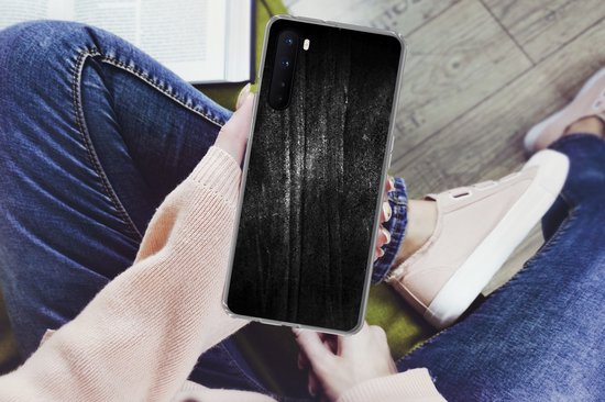 Telefoonhoesje met zwarte metaalprint met glitter, vastgehouden door een persoon zittend in een stoel.