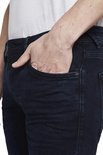 Close-up van de zak van een donkerblauwe jeans met een klein metalen logo.